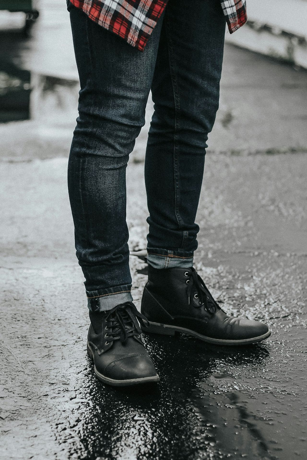 person wearing black denim jeans and pair of black leather boots